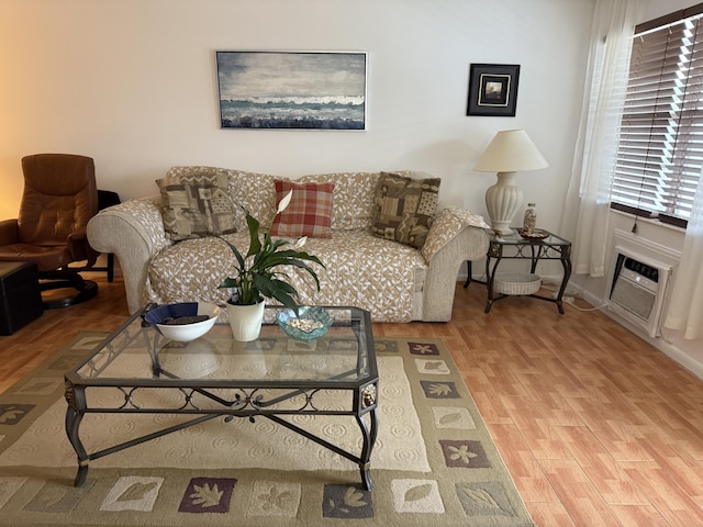 living area with wood finished floors, baseboards, and an AC wall unit