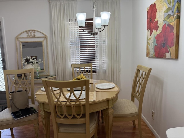 dining area with baseboards, an inviting chandelier, and wood finished floors