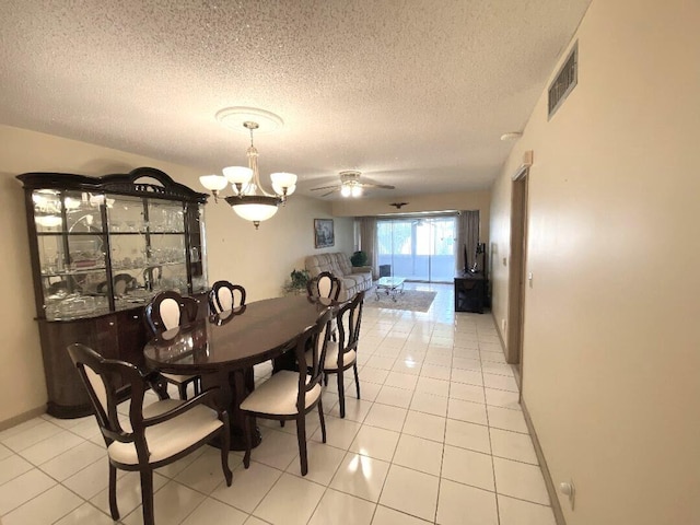 dining area with a textured ceiling, light tile patterned floors, a chandelier, ceiling fan, and baseboards