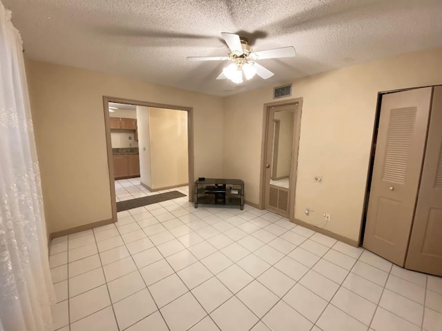 unfurnished bedroom featuring a textured ceiling, baseboards, light tile patterned floors, ceiling fan, and a closet