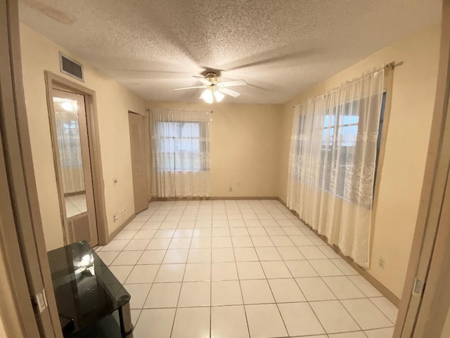 spare room with ceiling fan, a textured ceiling, and baseboards