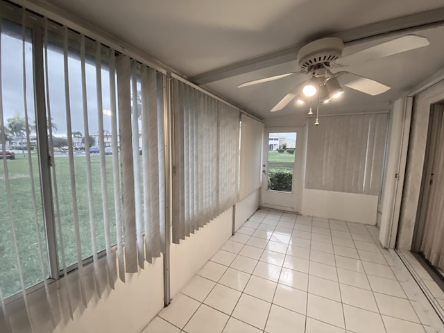 unfurnished sunroom with ceiling fan and tile patterned flooring