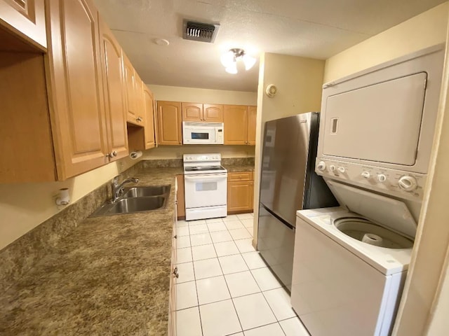 kitchen featuring white appliances, stacked washer / dryer, a sink, light brown cabinets, and light tile patterned flooring