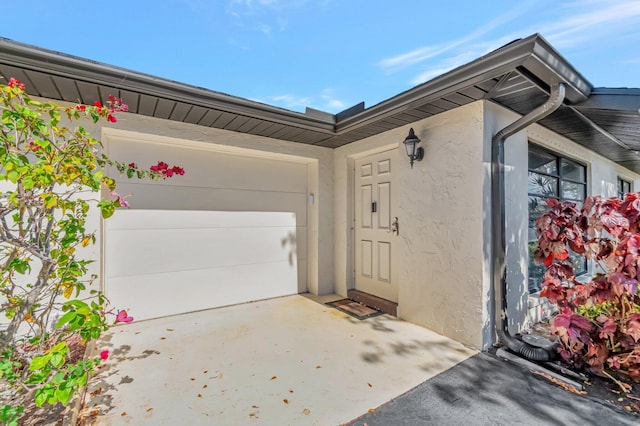 4875 Hawkwood Rd Unit B, Boynton Beach, FL 33436 - view of exterior entry with concrete driveway, a garage, and stucco siding