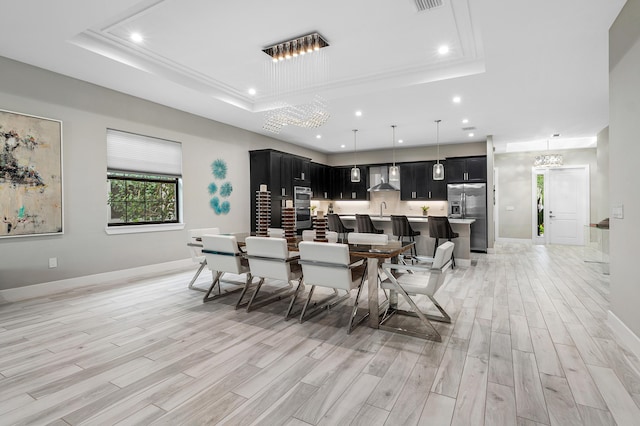 dining area with a tray ceiling, light wood-style floors, recessed lighting, and baseboards
