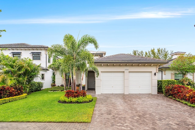 view of front of property with decorative driveway, an attached garage, stucco siding, a front lawn, and a tiled roof