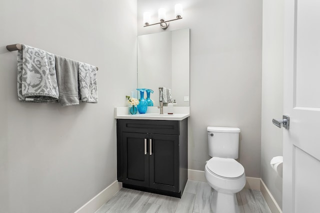 bathroom featuring toilet, baseboards, and vanity