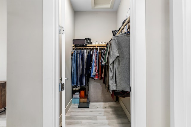 walk in closet with wood finished floors and attic access