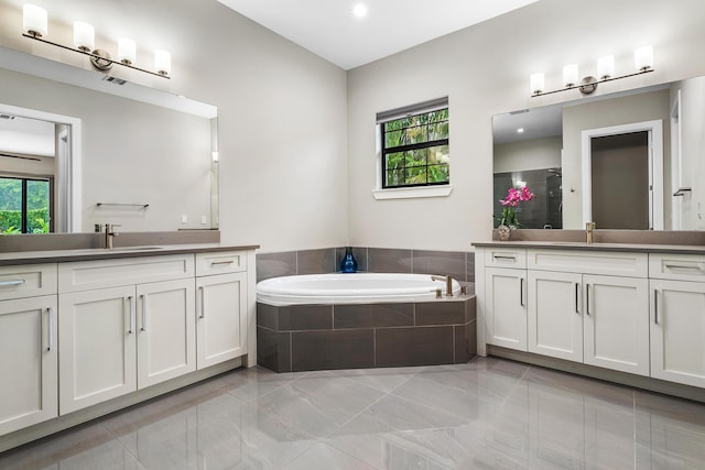 bathroom featuring a shower stall, a sink, two vanities, and a bath