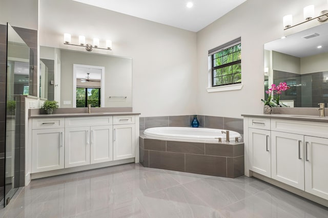 full bath featuring a bath, a shower stall, and two vanities