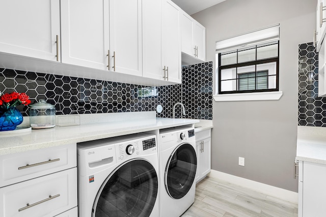 washroom featuring washing machine and dryer, baseboards, a sink, light wood-type flooring, and cabinet space