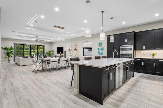 kitchen with dark cabinets, open floor plan, stainless steel appliances, and a sink