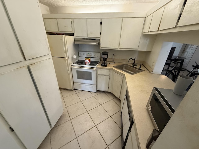 kitchen with white appliances, light countertops, a textured ceiling, under cabinet range hood, and a sink