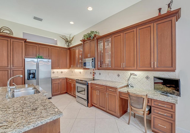 kitchen with brown cabinetry, stainless steel appliances, visible vents, and a sink