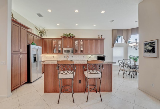 kitchen featuring an inviting chandelier, stainless steel appliances, decorative backsplash, and visible vents