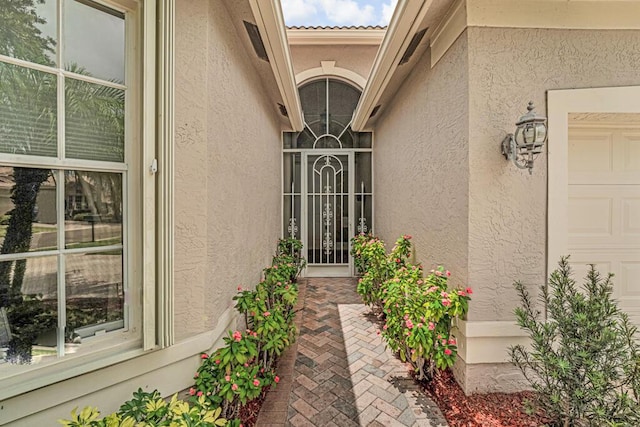 doorway to property with an attached garage and stucco siding