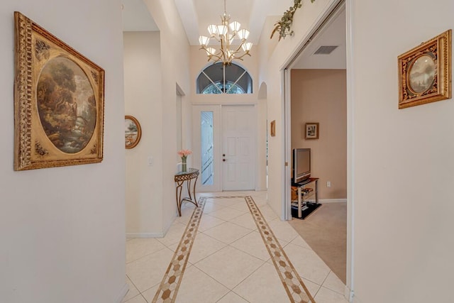 foyer entrance featuring an inviting chandelier, visible vents, baseboards, and a towering ceiling