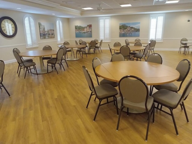 dining area with a raised ceiling, light wood-style flooring, and a wealth of natural light