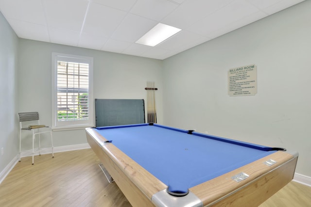 recreation room with baseboards, a drop ceiling, and wood finished floors
