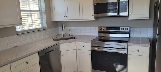 kitchen featuring a sink, tasteful backsplash, stainless steel appliances, and white cabinetry