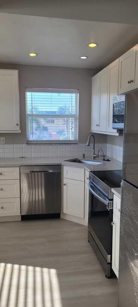 kitchen with appliances with stainless steel finishes, a wealth of natural light, a sink, and light wood-style floors