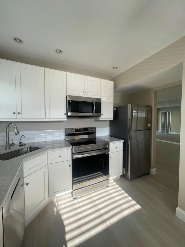 kitchen with a sink, light countertops, stainless steel appliances, white cabinetry, and light wood-type flooring
