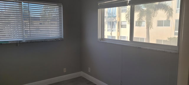 unfurnished room with baseboards and a wealth of natural light