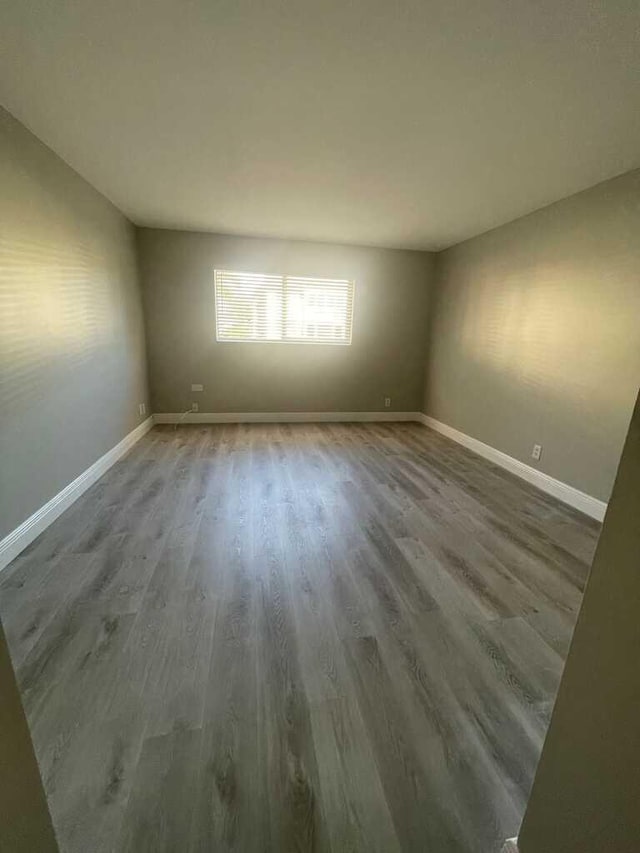 empty room with baseboards and wood finished floors