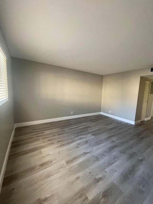 empty room featuring baseboards, dark wood-style flooring, and visible vents
