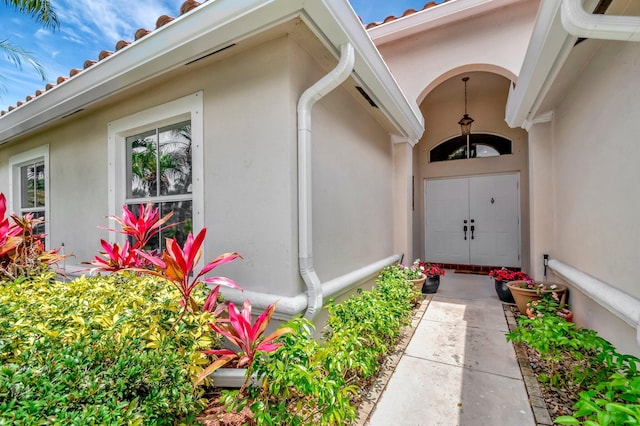 doorway to property featuring stucco siding and a tile roof