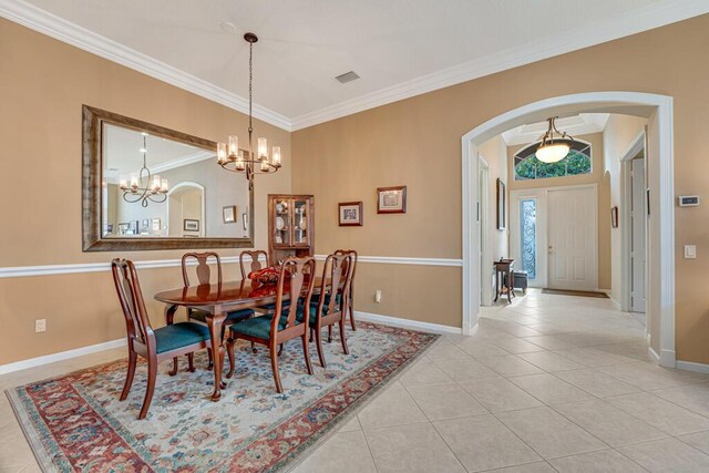 dining space featuring arched walkways, crown molding, baseboards, a chandelier, and light tile patterned floors