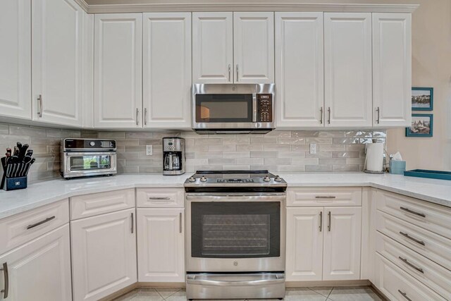 kitchen with stainless steel appliances, tasteful backsplash, white cabinets, and light tile patterned floors