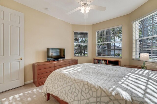 bedroom with light carpet, baseboards, and a ceiling fan