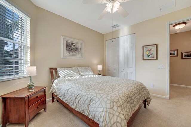 bedroom with light carpet, a closet, baseboards, and a ceiling fan