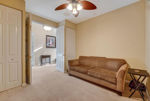 living area with light colored carpet, ceiling fan, and baseboards