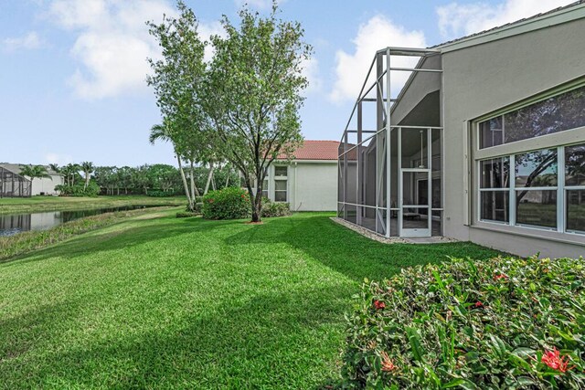 view of green lawn with a water view and a lanai
