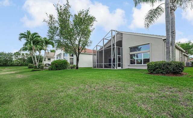 rear view of property featuring stucco siding, a lawn, and glass enclosure