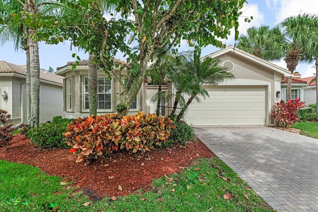 view of front of property with decorative driveway, a garage, and stucco siding