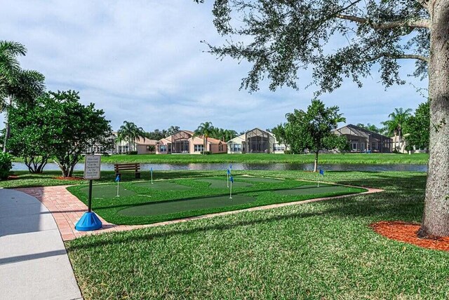view of community featuring an area to practice putting, a lawn, a water view, and a residential view