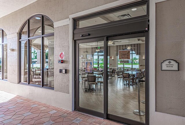 doorway to property featuring stucco siding and visible vents