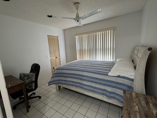 tiled bedroom with ceiling fan and a textured ceiling