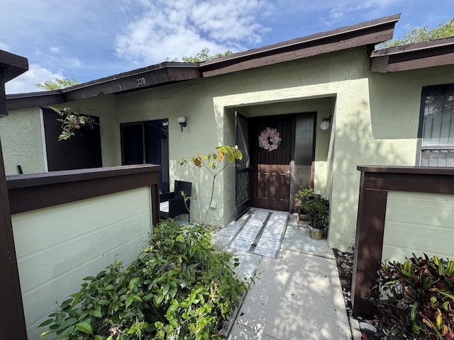 property entrance with stucco siding and a garage