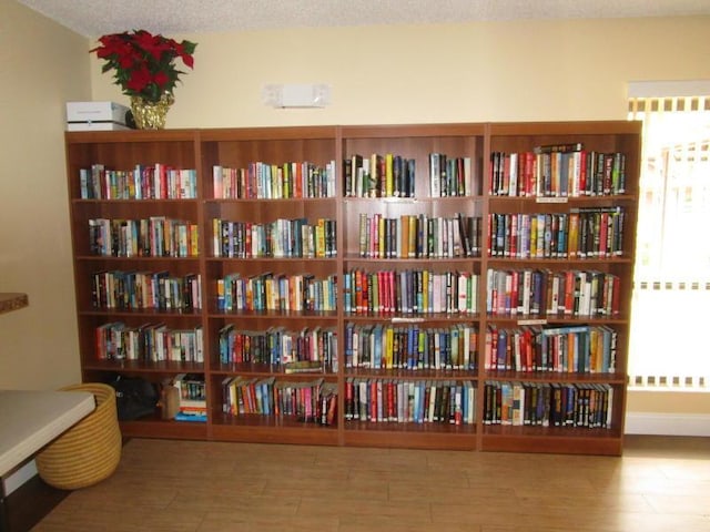 living area with baseboards, bookshelves, and wood finished floors