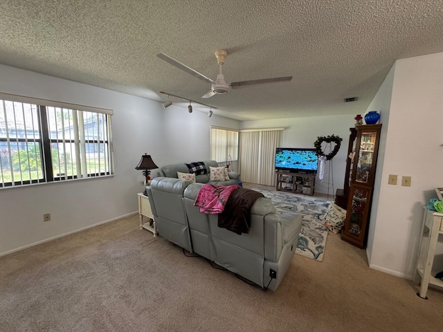 interior space featuring a textured ceiling, baseboards, ceiling fan, visible vents, and rail lighting