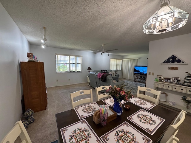 dining space featuring a textured ceiling, carpet flooring, and a ceiling fan