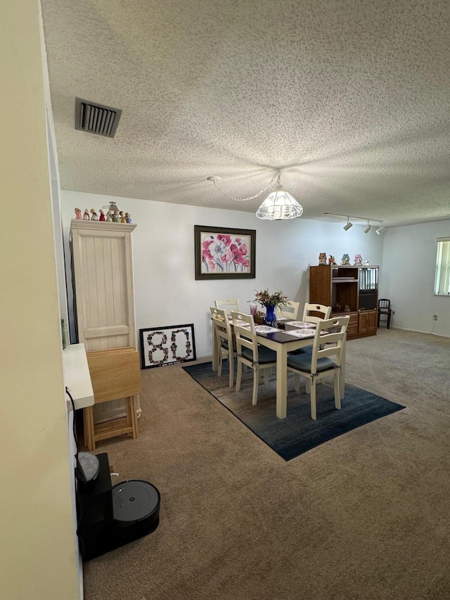 dining area with carpet flooring, visible vents, and a textured ceiling