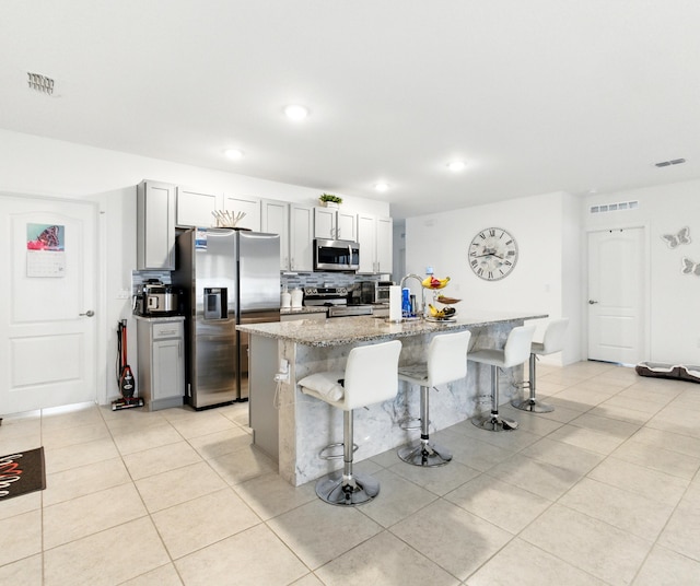 3020 SW Ann Arbor Rd, Port Saint Lucie, FL 34953 - kitchen with appliances with stainless steel finishes, a kitchen breakfast bar, light stone counters, light tile patterned flooring, and recessed lighting