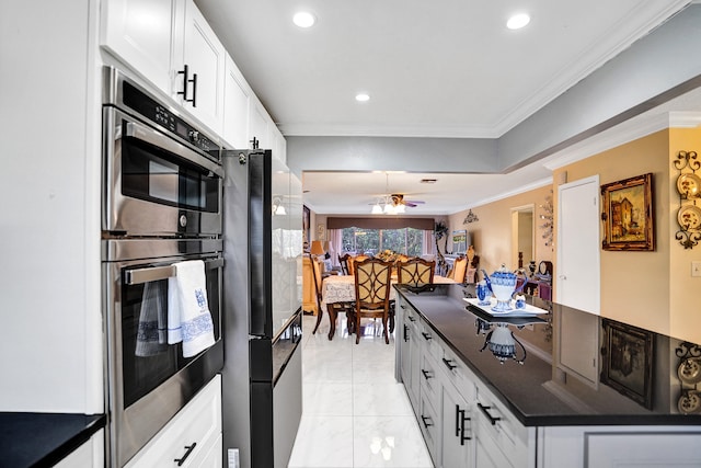 kitchen featuring freestanding refrigerator, stainless steel double oven, white cabinetry, crown molding, and dark countertops