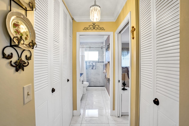 hallway with ornamental molding, baseboards, and marble finish floor