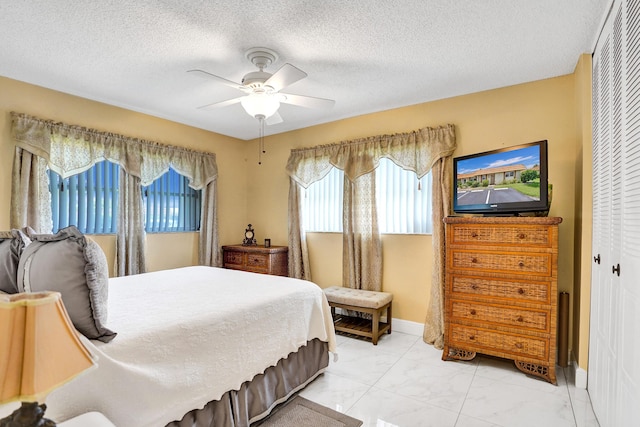 bedroom with a textured ceiling, a closet, a ceiling fan, and marble finish floor
